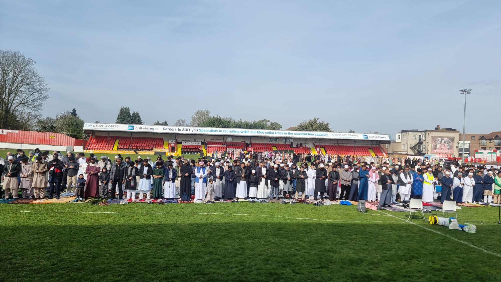 Worshippers lined up across the pitch with the stand behind