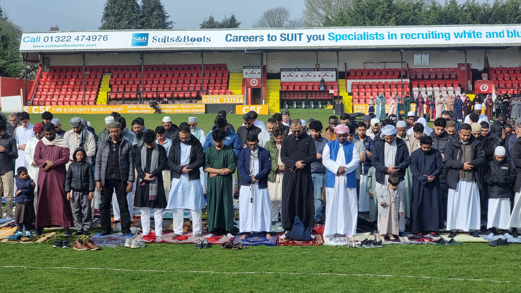 Front rows of worshippers with prayer mats on the grass
